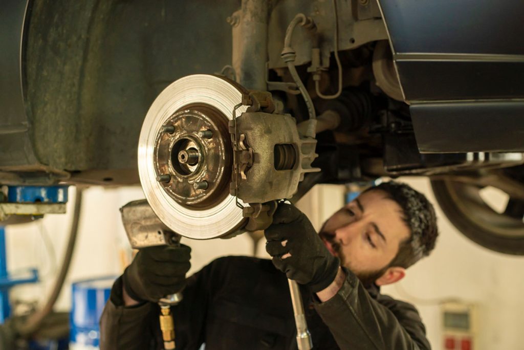 Zamena kočnica na automobilu od strane mehaničara u servisu.