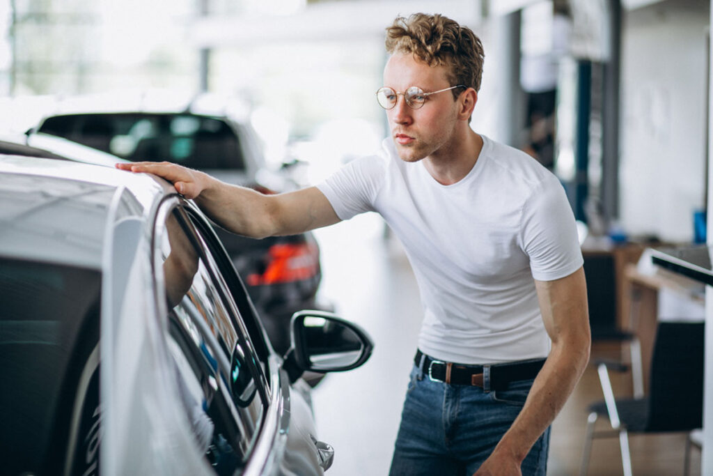 Momak proverava spoljašnost automobila tokom kupovine