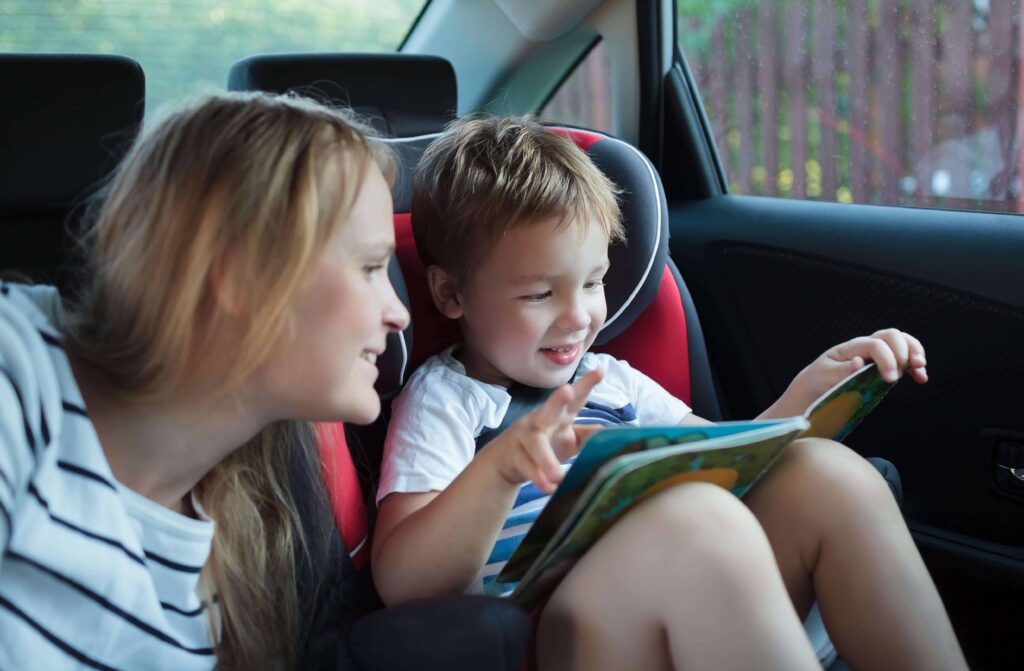 Dete se zabavlja gledanjem slikovnice tokom putovanja automobilom.