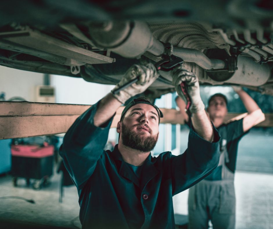 Izduvni sistem automobila pregledaju dva mehaničara.