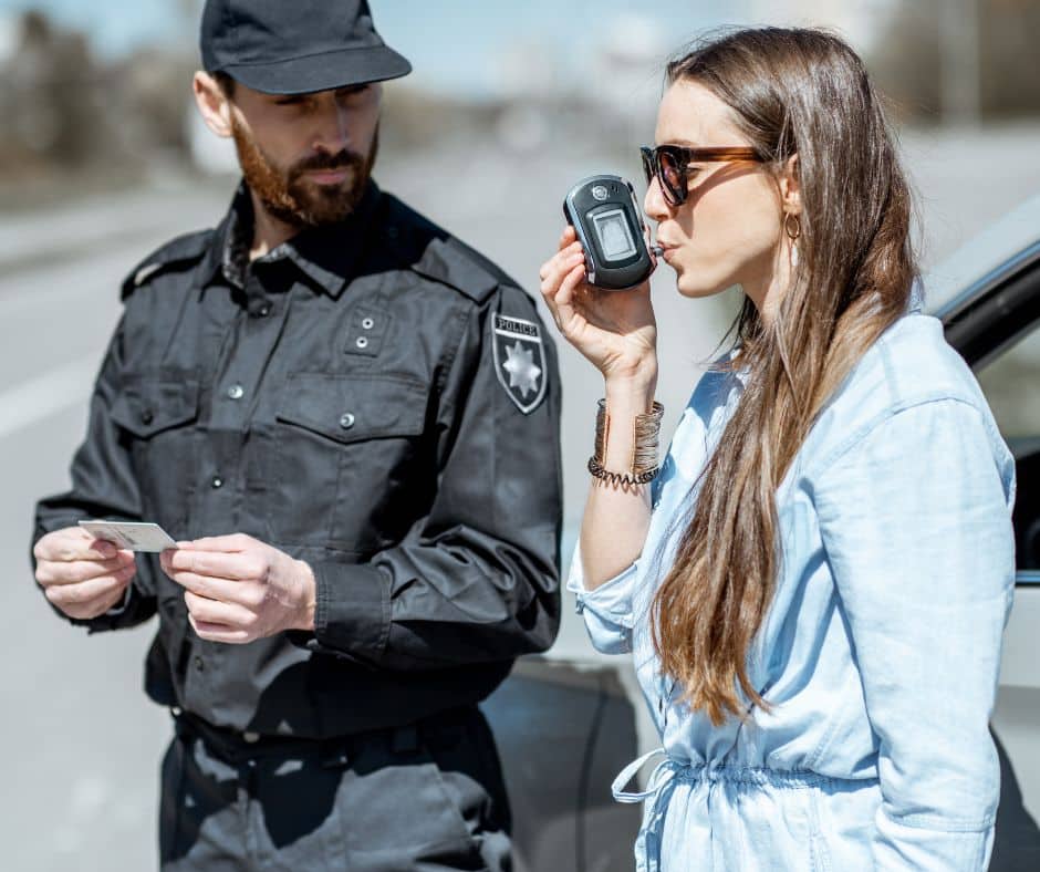 Policajac proverava koliko alkohola u krvi ima vozač pomoću alko testa.