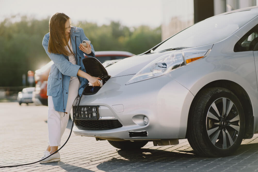 Devojka proverava punjenje i stanje baterije tokom probne vožnje polovnog električnog automobila.