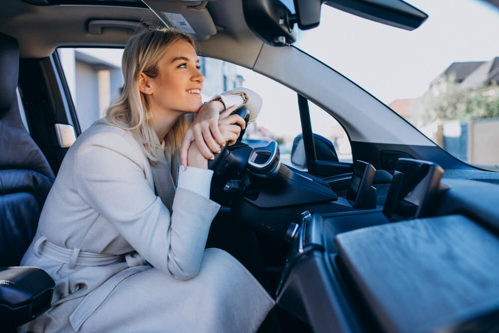Devojka u kupljenom polovnom električnom automobilu.
