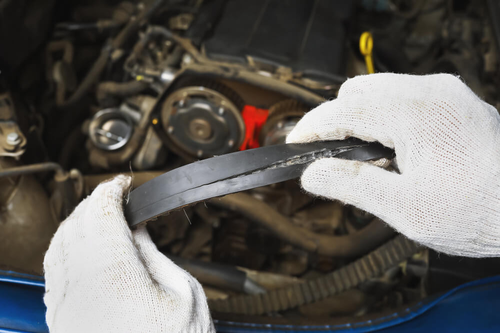 Veliki servis cena 4 Automehaničar prikazuje pucanje zupčastog kaiša kod automobila sa zadnje strane.