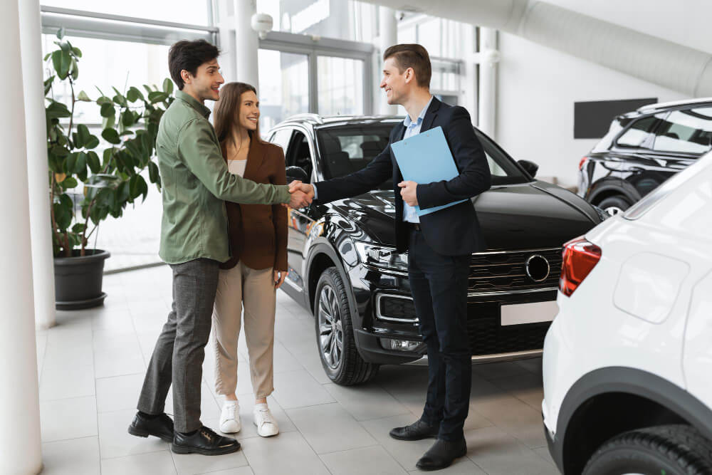 Mladi par razgleda nove automobile u salonu.